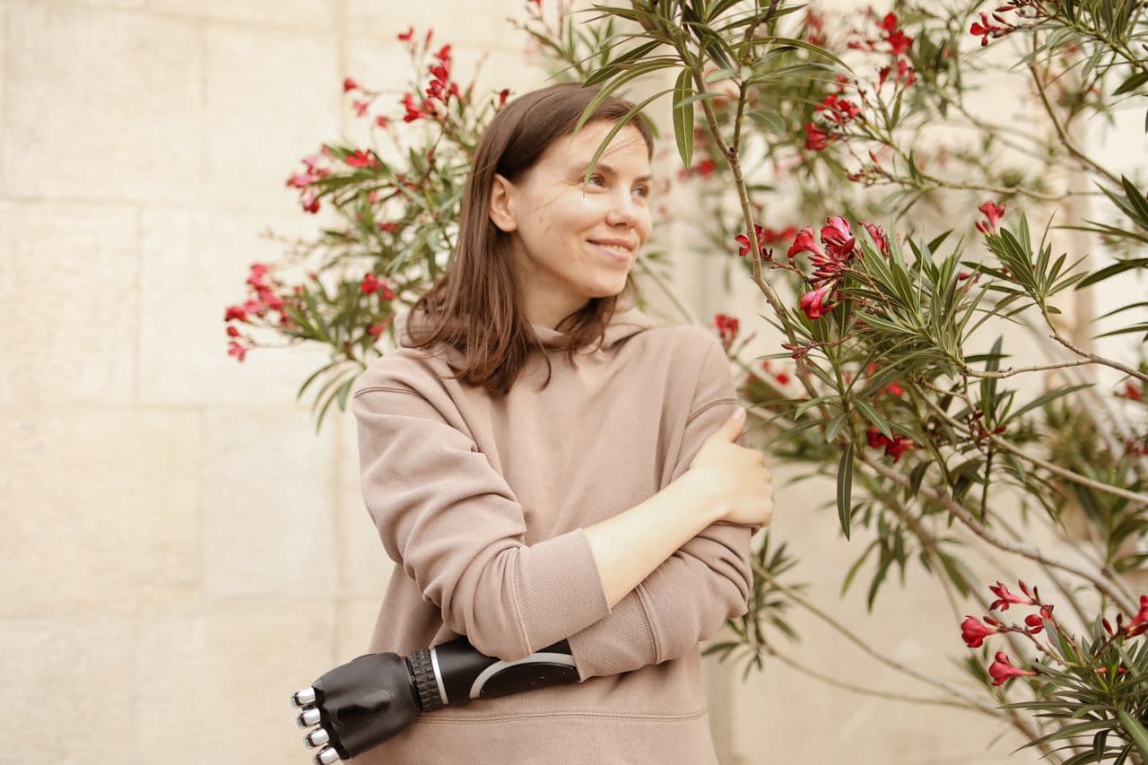 A woman smiling beside flowering greenery
